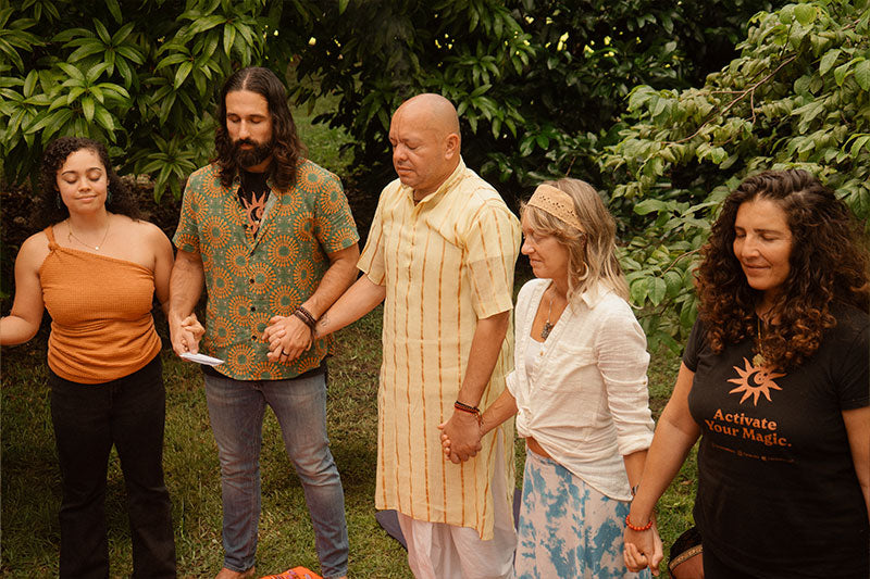 Group of five people standing outdoors with greenery in the background