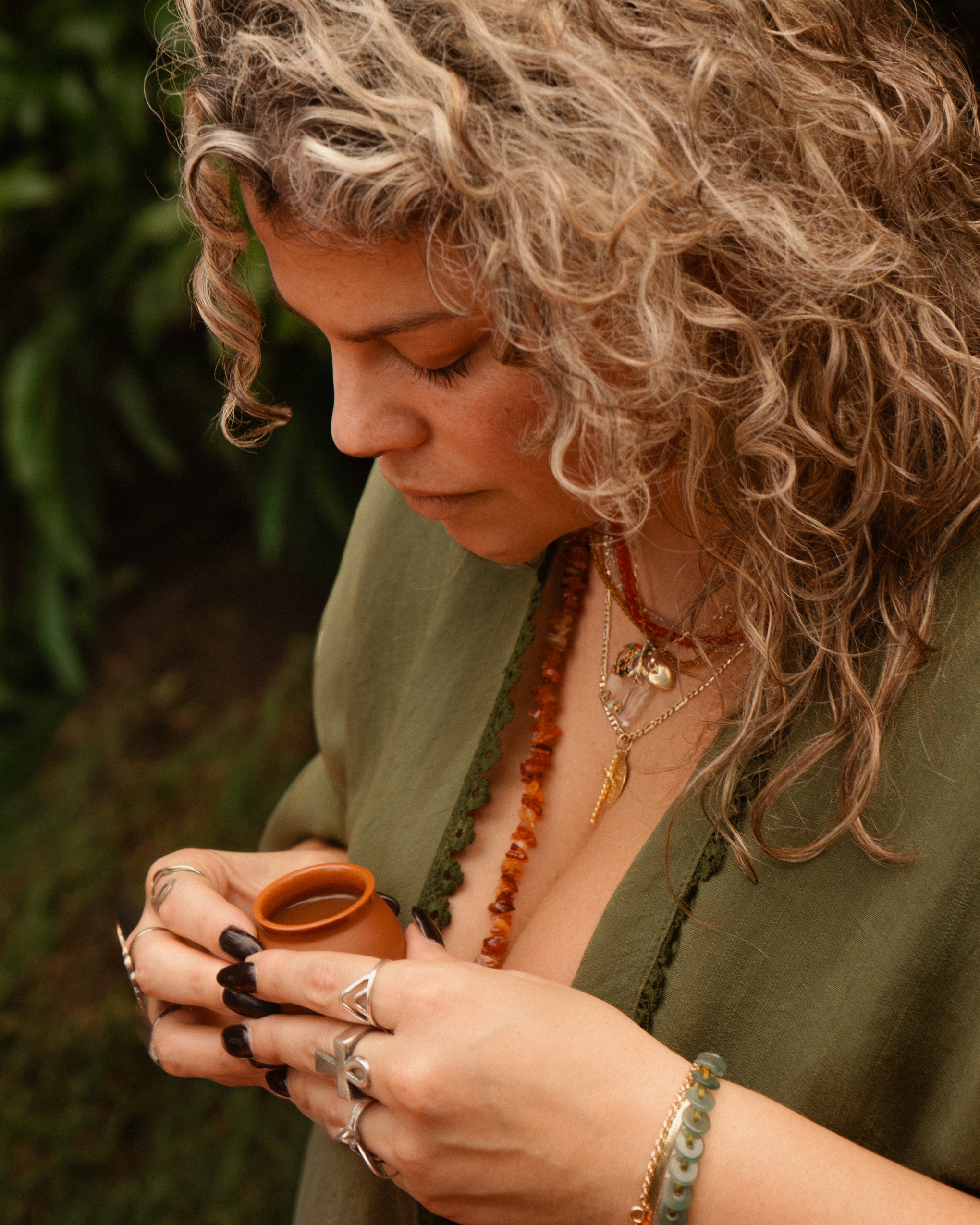 Woman with curly hair holding a small container with cacao drink